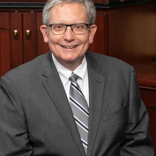 Robert H. Gallagher sitting in front of a wooden cabinet.